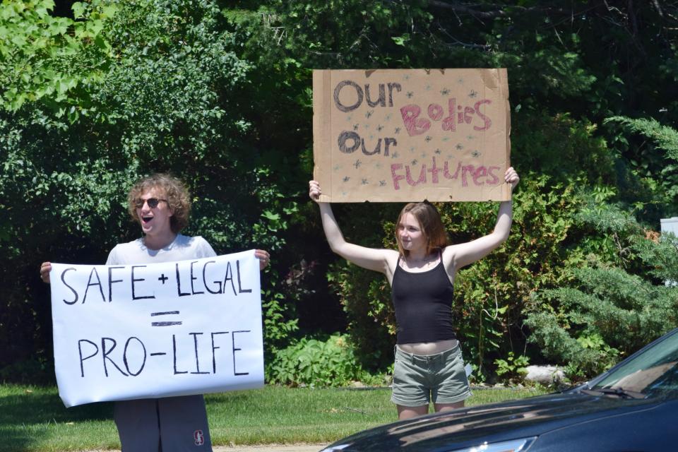 Protesters with signs reading "Safe + Legal = Pro-life" and "Our bodies, Our futures" stand along US-31 as cars honk in support of the protesters on Sunday, July 3.