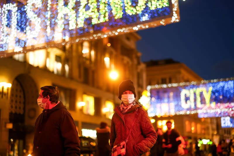 Pedestrians illuminated by Christmas lights walk through Oxford Street amid the coronavirus disease (COVID-19) outbreak in London