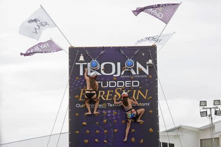 Party goers scale a climbing wall sponsored by Trojan condoms during spring break festivities in Panama City Beach, Florida March 13, 2015. REUTERS/Michael Spooneybarger