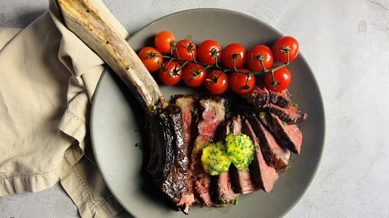 tomahawk steak with tomatoes on gray plate