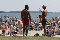 FILE - In this June 5, 2021, file photo, two men talk as crowds gather on L Street Beach in the South Boston neighborhood of Boston. COVID-19 deaths in the U.S. have dipped below 300 a day for the first time since the early days of the disaster in March 2020, while the number of Americans fully vaccinated has reached about 150 million. (AP Photo/Michael Dwyer, File)