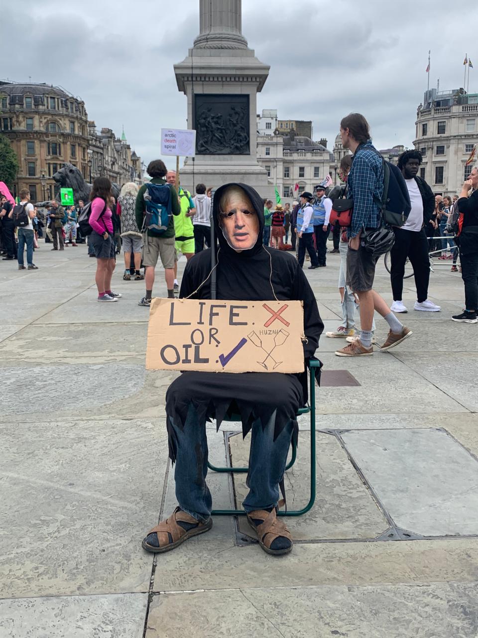 A man wearing a Boris Johnson face mask holds an anti-fossil fuel placard in Trafalgar Square (Sam Hancock/The Independent)