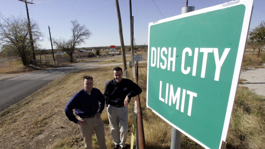 DISH city mayor Bill Merritt, left, stands with Michael Neuman, president of Dish Network, after unveiling a DISH City Limit sign, on Nov. 16, 2005, in DISH, Texas. The city of Clark renamed itself DISH, Texas, for a decade. (AP Photo/Donna McWilliam)