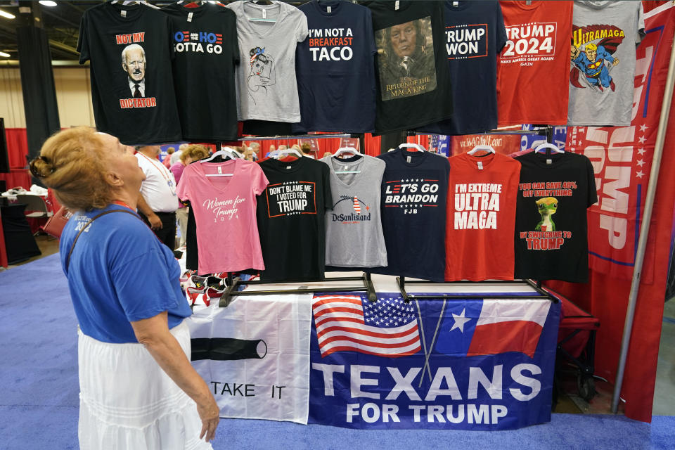 Maura C Jans of Rio Rancho, N.M., laughs as she looks at T-shirts for sale at the Conservative Political Action Conference (CPAC) in Dallas, Thursday, Aug. 4, 2022. Hungarian Prime Minister Viktor Orban is scheduled to speak at the conference Thursday and former President Donald Trump is scheduled for Saturday. (AP Photo/LM Otero)