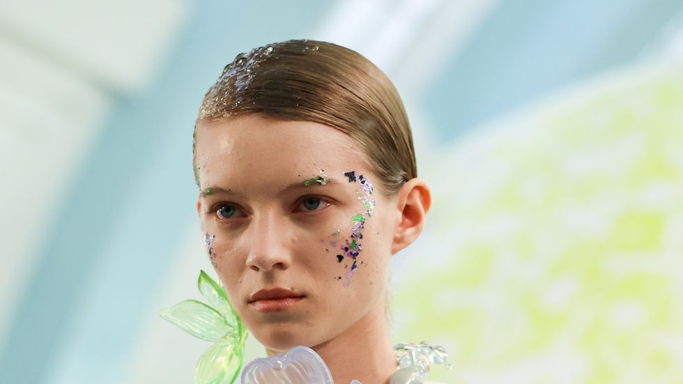 a model wears gigantic floral jewelry at a runway show