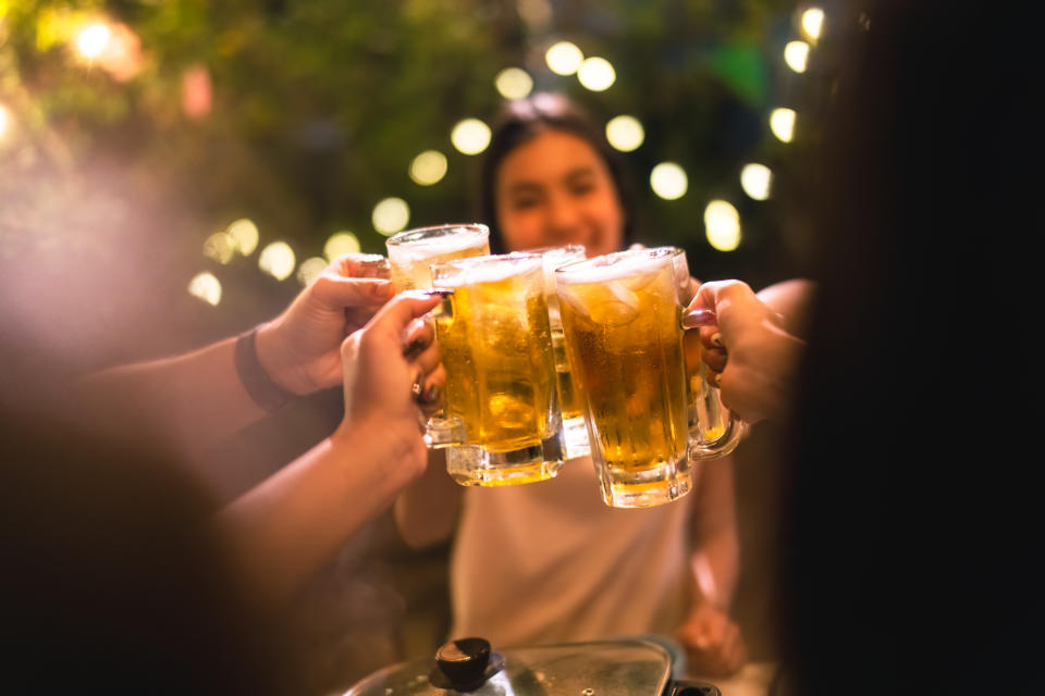 Evening group of friends drinking beer and clinking glasses.