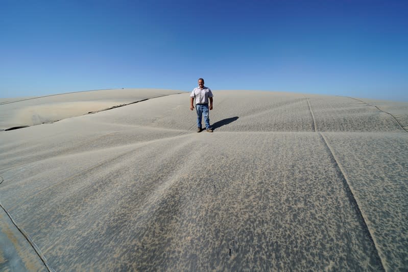 Dairy farmer Joey Airoso stands on top of a methane collecting dome that covers one of his farm's waste collecting ponds in Pixley, California