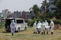 People, wearing protective suits, carry a body of a man who died due to coronavirus disease (COVID-19), before his burial at a graveyard in Dhaka