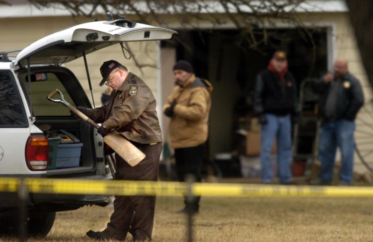A Peoria County sheriff's deputy examines one of a collection of shovels removed Wednesday from the garage at the home of Larry D. Bright at 3418 W. Starr Court in this 2005 file photo. Bright, charged with the deaths of multiple women, is one of a number of infamous serial killers who operated in Illinois.