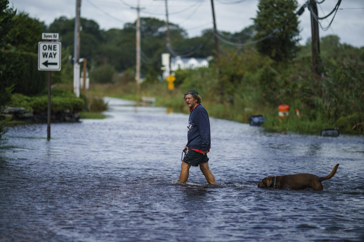 A resident in Narragansett, R.I., wades through a flooded street on Thursday. 