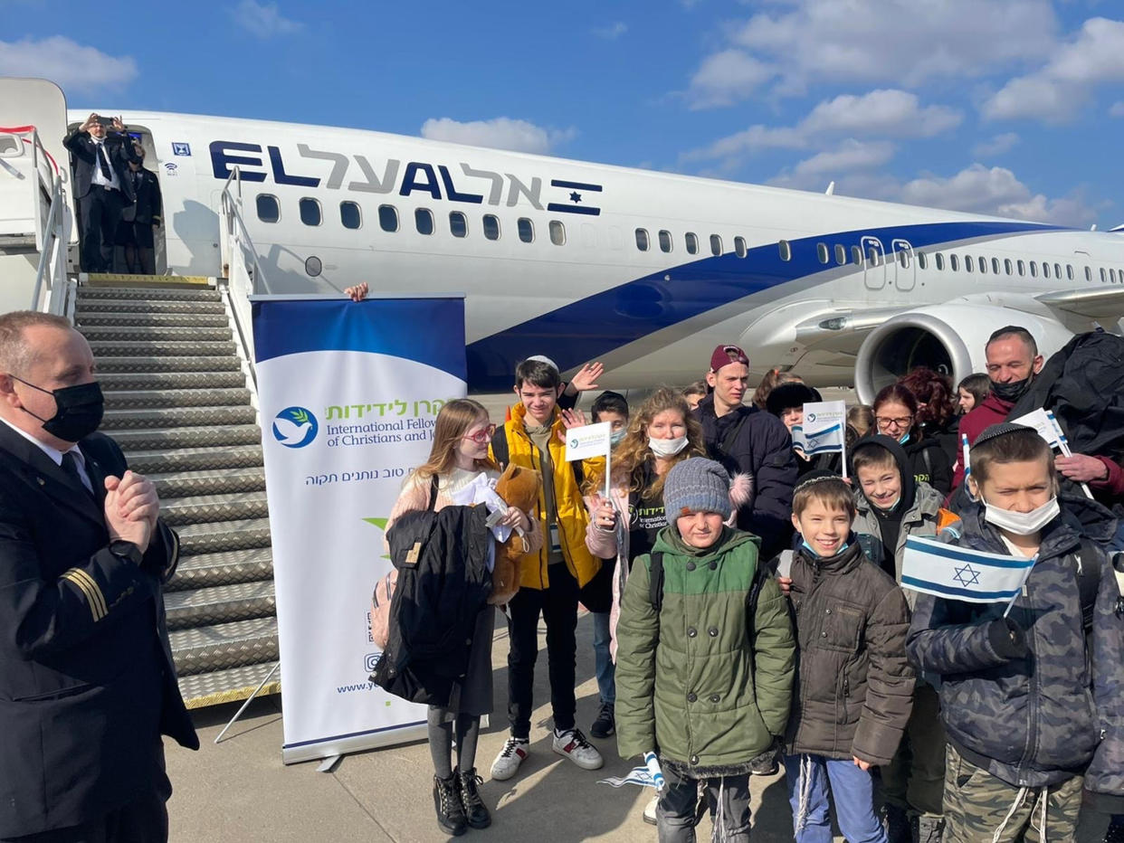 Some of the children pictured near the plane that delivered them safely to Israel, along with the caregivers and volunteers who made it possible. (Courtesy The International Fellowship of Christians and Jews)