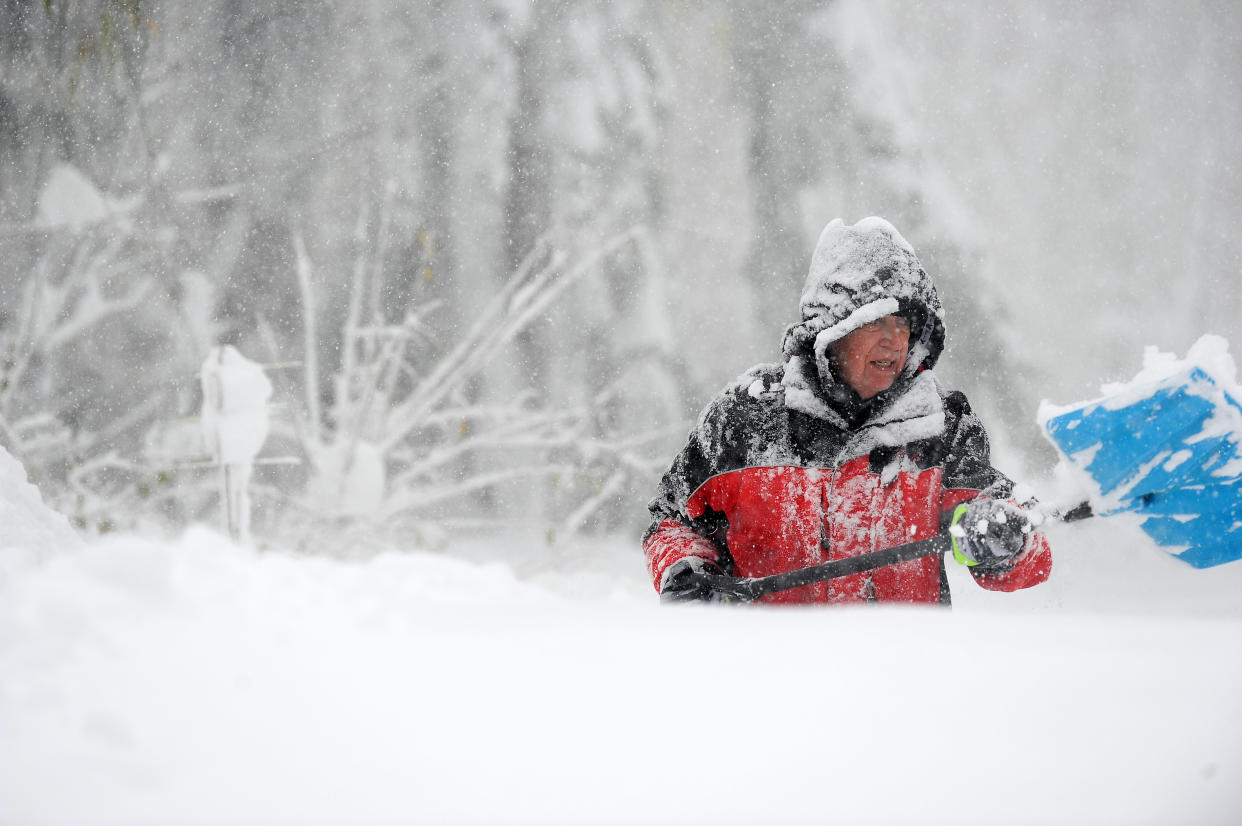 A man with a shovel digs out during a snowfall of more than 6 feet.