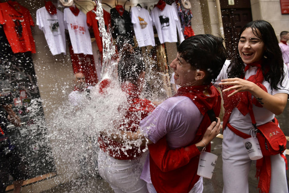 Water is thrown on revelers celebrating the launch of the 'Chupinazo' rocket, to mark the official opening of the 2022 San Fermin fiestas in Pamplona, Spain, Wednesday, July 6, 2022. The blast of a traditional firework opened Wednesday nine days of uninterrupted partying in Pamplona's famed running-of-the-bulls festival which was suspended for the past two years because of the coronavirus pandemic. (AP Photo/Alvaro Barrientos)