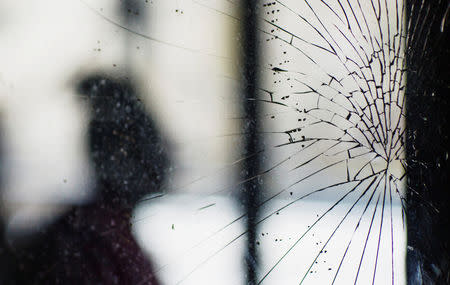 FILE PHOTO: A man stands behind shattered glass at the front of New York City Housing Authority (NYCHA) housing that remains without power in the Queens borough neighborhood of Edgemere in New York, U.S., November 8, 2012. REUTERS/Lucas Jackson/File Photo