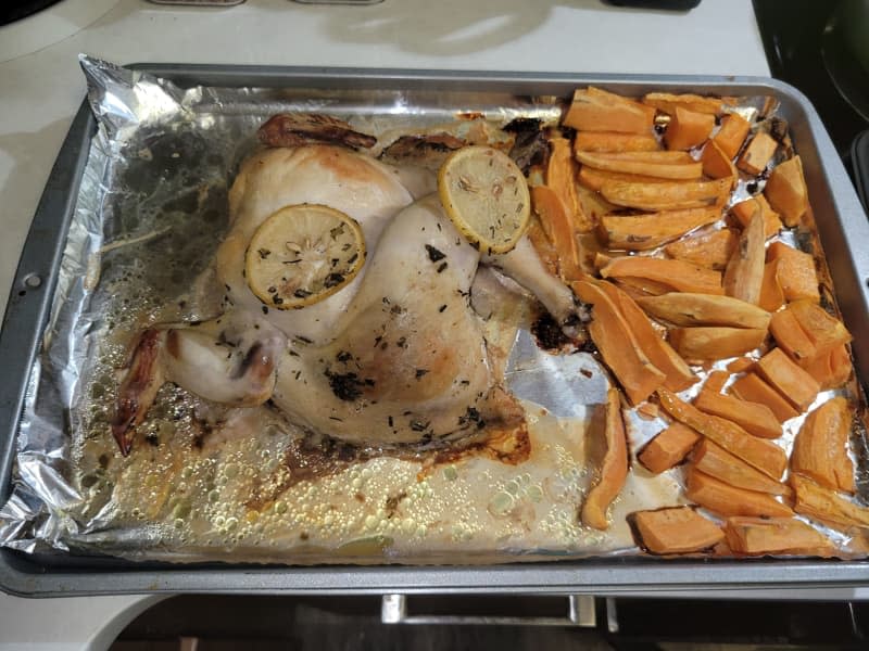Cooked chicken and sweet potato fries on a baking sheet