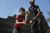 Alejandro, 9, catches bricks to pass over to a man who puts them in the kiln at a brick factory run by his uncles in Tobati, Paraguay, Monday, Aug. 31, 2020. Members of brickmaking families said school closures due to COVID-19, scheduled to last at least until December, have led to many children and adolescents working longer hours, making it difficult to complete their virtual schoolwork. (AP Photo/Jorge Saenz)