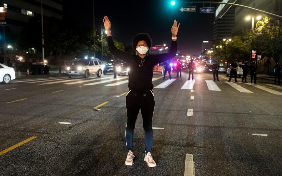 A demonstrator stands at an intersection during a protest Wednesday, May 27, 2020, in Los Angeles - AP