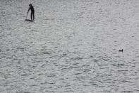 A man enjoys a paddleboard at Enoshima, the venue of sailing competitions at the Tokyo 2020 Olympics, in Fujisawa, near Tokyo, Tuesday, April 6, 2021. Many preparations are still up in the air as organizers try to figure out how to hold the postponed games in the middle of a pandemic. (AP Photo/Koji Sasahara)