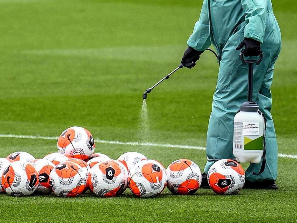 A member of staff at Liverpool's Melwood training ground disinfects footballs: Liverpool FC via Getty Images