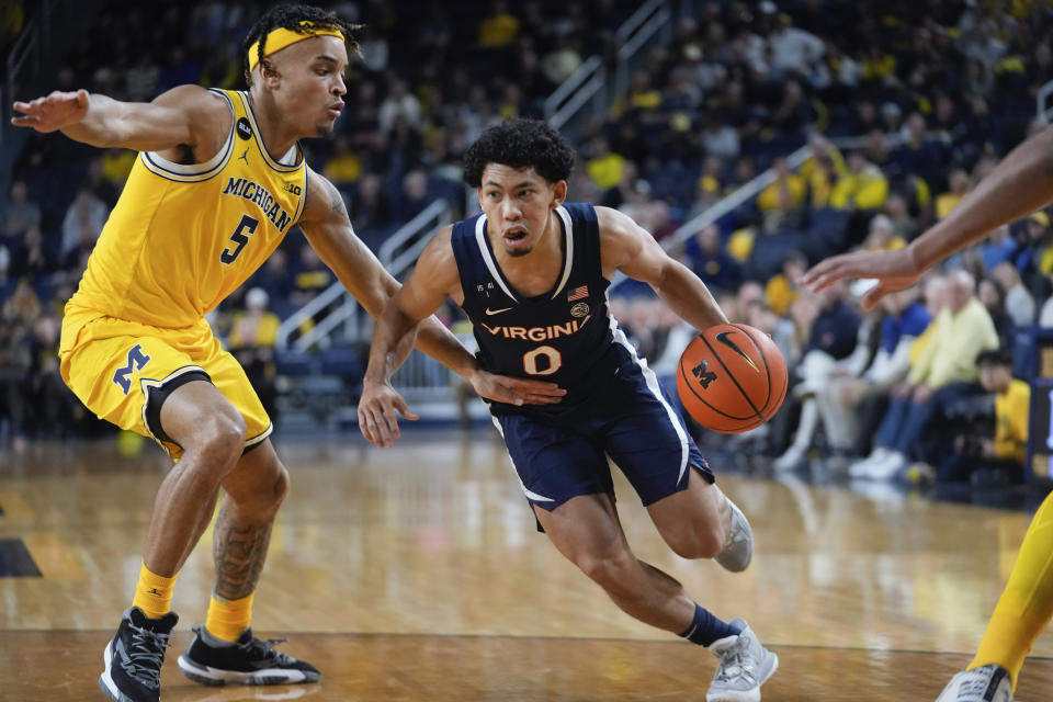 Virginia guard Kihei Clark (0) drives on Michigan forward Terrance Williams II (5) in the first half of an NCAA college basketball game in Ann Arbor, Mich., Tuesday, Nov. 29, 2022. (AP Photo/Paul Sancya)