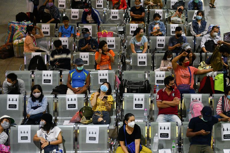 People wearing protective face masks, sit on social distancing benches at a bus station after many workers crowded the terminal station to return to their cities after many activities have been closed due to coronavirus disease (COVID-19) outbreak