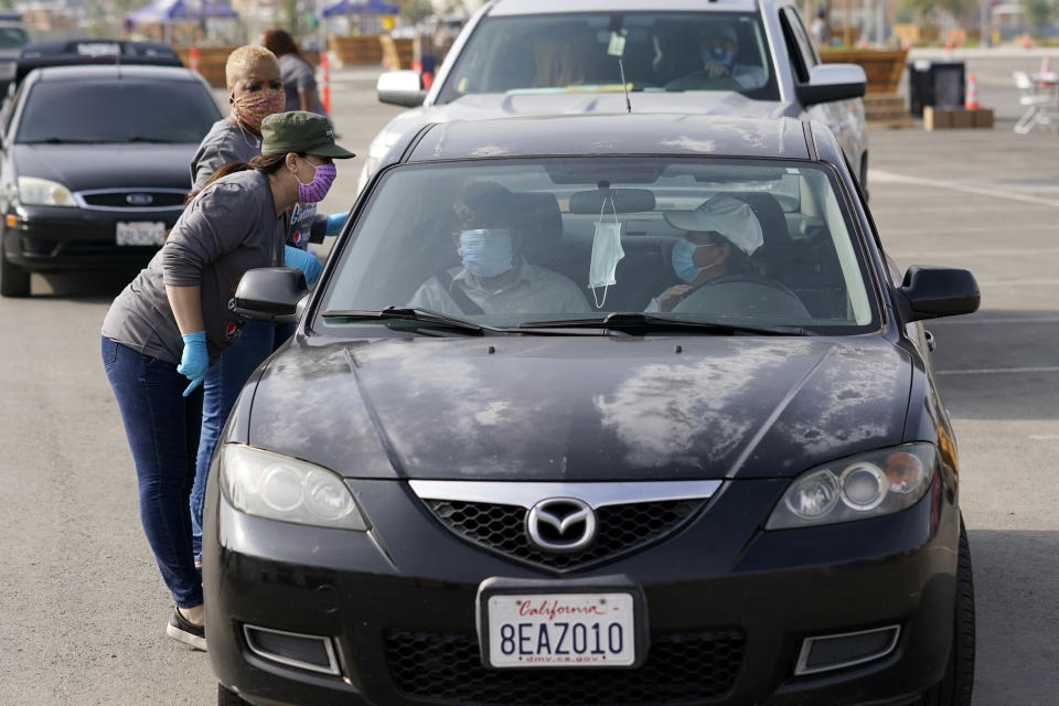 Volunteers serve motorists at a food distribution center set up at SoFi Stadium ahead of Thanksgiving and amid the COVID-19 pandemic, Monday, Nov. 23, 2020, in Inglewood, Calif. (AP Photo/Marcio Jose Sanchez)