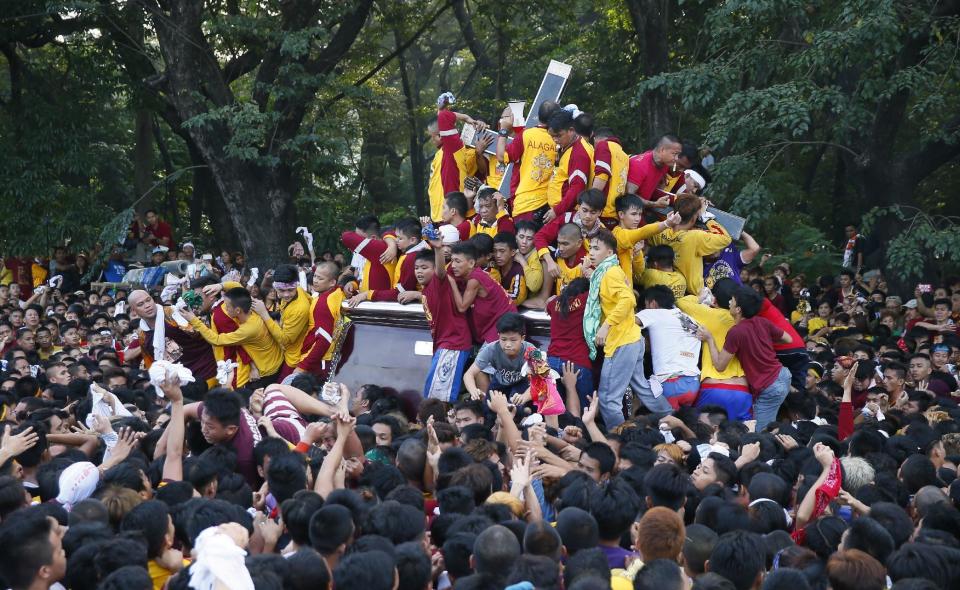 Filipino Roman Catholic devotees climb the carriage to kiss and rub with their towels the image of the Black Nazarene to celebrate its feast day Monday, Jan. 9, 2017 in Manila, Philippines. The raucous celebration drew tens of thousands of devotees in a barefoot procession for several hours around Manila streets and end up with several people injured. (AP Photo/Bullit Marquez)