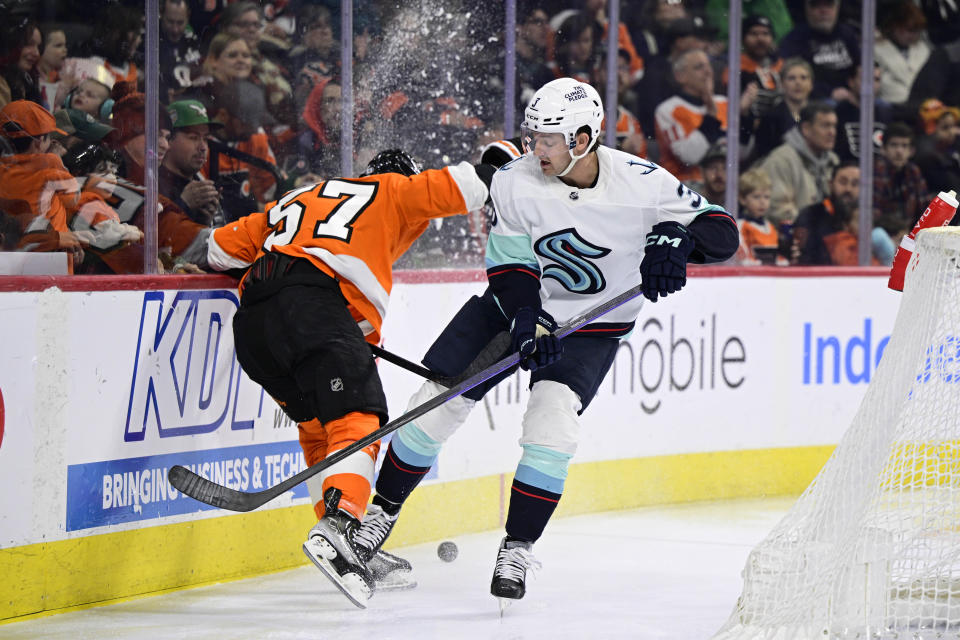 Seattle Kraken's Will Borgen and Philadelphia Flyers' Wade Allison (57) battle for the puck along the boards during the second period an NHL hockey game, Sunday, Feb. 12, 2023, in Philadelphia. (AP Photo/Derik Hamilton)