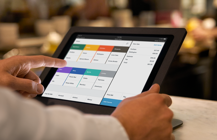 A person holding a tablet displaying the Square for Restaurants platform.