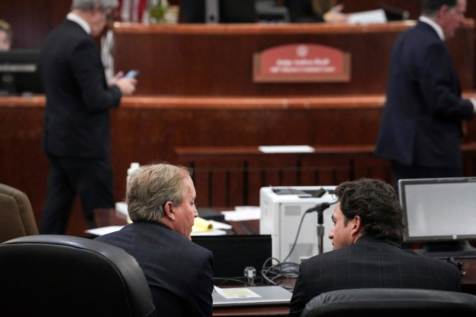 Texas Attorney General Ken Paxton, front left, speaks with his defense attorney Anthony Osso Jr. at the hearing in Houston.