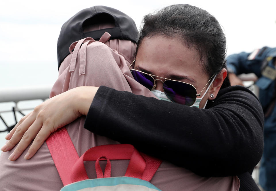 Relatives of the victims of Sriwijaya Air flight SJ-182 comfort each other during a memorial ceremony held on the deck of Indonesian Navy Ship KRI Semarang that sails in the Java Sea where the plane crashed on Jan. 9 killing all of its passengers, near Jakarta in Indonesia, Friday, Jan. 22, 2021. (AP Photo/Tatan Syuflana)