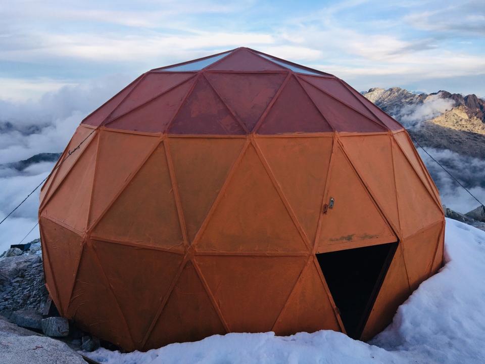 A geodesic dome surrounded by snow on a mountain.