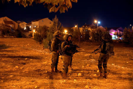 Israeli soldiers chat as they guard the Israeli settlement Adam after a Palestinian assailant stabbed three people and then was shot and killed, according to the Israeli military, in the occupied West Bank, July 26, 2018. REUTERS/Ronen Zvulun