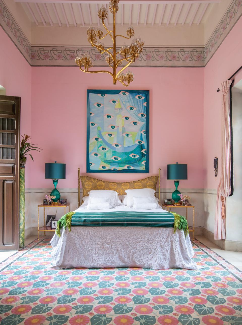 One of Skouras’s Currey & Company light fixtures hangs in the primary bedroom, where she also designed the rose quartz−and−gold leaf bedsides tables and the headboard, which is upholstered in a Fortuny fabric. The lamps are vintage Murano and the painting is by David Serrano.