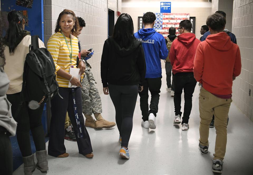 In this Thursday, Nov. 7, 2019, photo, Jade Gopie, second from left, principal at Crosby High School, left, watches students as they pass between classes in Waterbury, Conn. While students in the Waterbury public school district are predominantly black and Hispanic, the vast majority of its educators, as in school districts across the country, are white. (AP Photo/Jessica Hill)