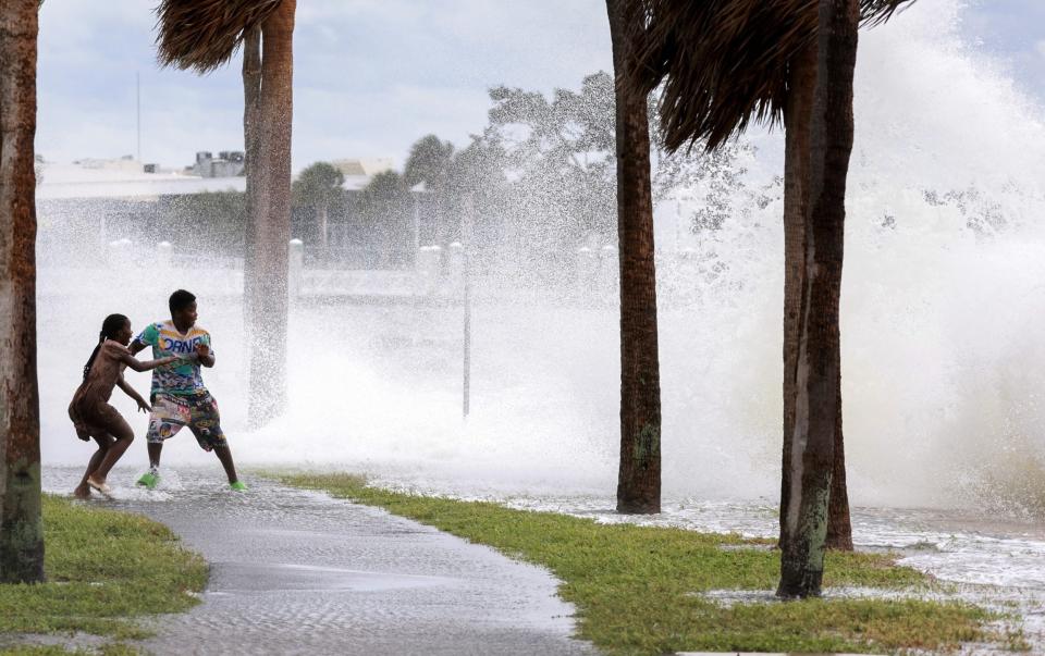 People are splashed by churning surf from Tampa Bay as Hurricane Helene passes offshore in Florida