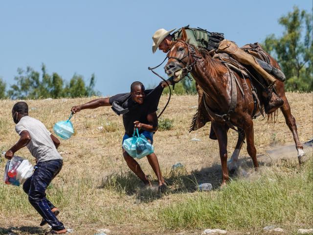 An agent for US Border Patrol tries to stop a migrant entering the US (AFP via Getty Images)