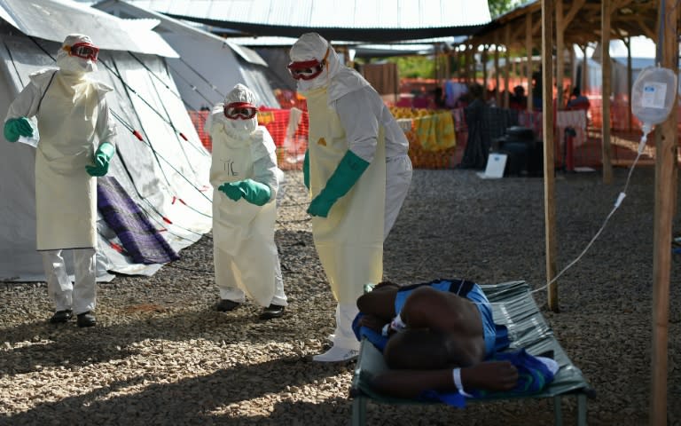 Health workers wearing protective equipment dance as they try to cheer up an Ebola patient at Kenema treatment center in Sierra Leone, run by the Red cross Society on November 15, 2014