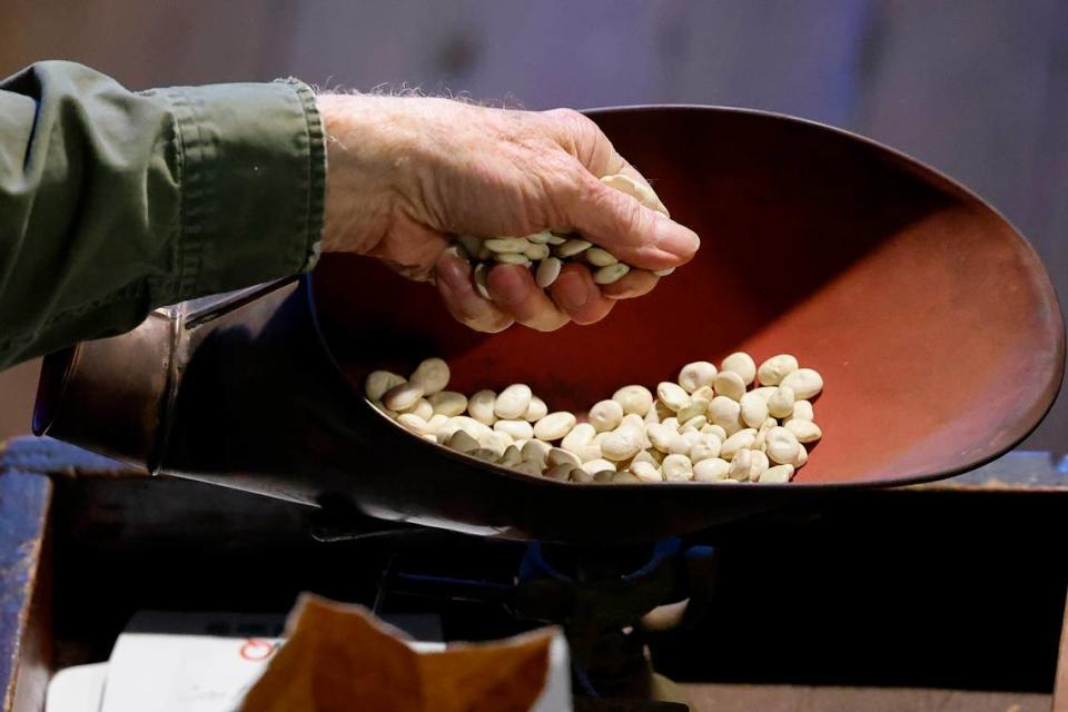 Silas Davis, of Charlotte, N.C., owner of the Davis General Store, weighs handfuls of beans to fulfill an order at the Davis General Store in Charlotte, N.C., Tuesday, April 19, 2022.