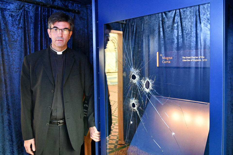 The Reverend Canon Nicholas Charles Papadopulos beside the glass case, which houses the Magna Carta, inside the Chapter House at Salisbury Cathedral with hammer holes in the glass after a 45-year-old man has been arrested on suspicion of its attempted theft.