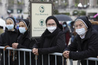 A group of nuns wearing face masks hold rosaries while waiting for the start of the religious ceremonies at the Catholic shrine in Fatima, Portugal, Thursday, May 13, 2021. In view of the coronavirus pandemic, the shrine has limited to 7,500 the number of pilgrims that can be present during this year's May 12 and 13 celebrations usually attended by hundreds of thousands. The sign reads " Speak low" and " Please don't take group photos". (AP Photo/Ana Brigida)