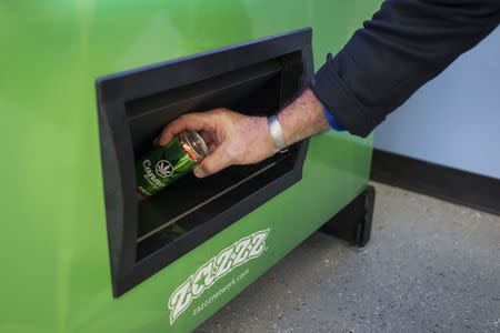 Stephen Shearin retrieves a can of Canna Energy Mango as he demonstrates the use of a ZaZZZ vending machine that contains cannabis flower, hemp-oil energy drinks, and other merchandise at Seattle Caregivers, a medical marijuana dispensary, in Seattle, Washington February 3, 2015. REUTERS/David Ryder