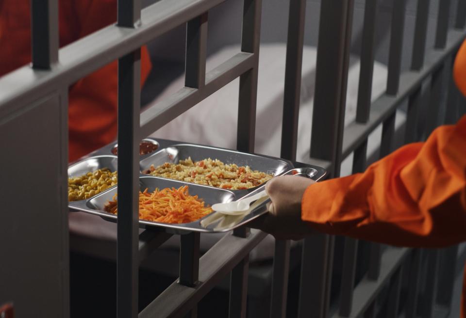 A jailer getting a meal from a barred slot