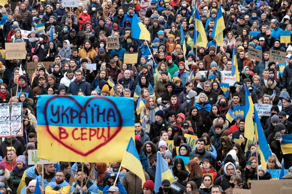 Protesters gather with blue and yellow flags and banners in Russian, one saying: 