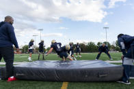 Gallaudet defensive players practice tackling drills during football practice at Hotchkiss Field, Tuesday, Oct. 10, 2023, in Washington. Gallaudet has been playing football since 1883, when it was known as the National Deaf-Mute College, and invented the huddle roughly a decade later. The school added a drum to replace whistles in 1970, and now present-day players and coaches carry on the program's rich history by winning games and continuing to innovate, most recently a helmet developed with AT&T that allows play calls to show up visually on a lens inside. (AP Photo/Stephanie Scarbrough)
