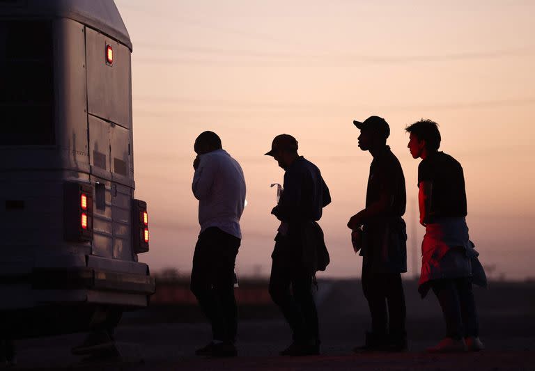 Inmigrantes que buscan asilo, esperan para abordar un autobús a un centro de procesamiento de la Patrulla Fronteriza de EE. UU., después de cruzar a Arizona desde México, el 11 de mayo de 2023 en Yuma, Arizona