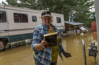 Lindi O'Brien picks up a commendation plaque to her father's police service from the barn of her parent's home badly damaged by the severe flooding in Fromberg, Mont., Friday, June 17, 2022. (AP Photo/David Goldman)