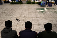 Three men from Honduras sit in a plaza at the border after being returned from the U.S. to Mexico, Thursday, May 13, 2021, in Reynosa, Mexico. The Biden administration has agreed to let up to about 250 people a day in the United States at border crossings with Mexico to seek refuge, part of negotiations to settle a lawsuit over pandemic-related powers that deny migrants a right to apply for asylum, an attorney said Monday. (AP Photo/Gregory Bull)