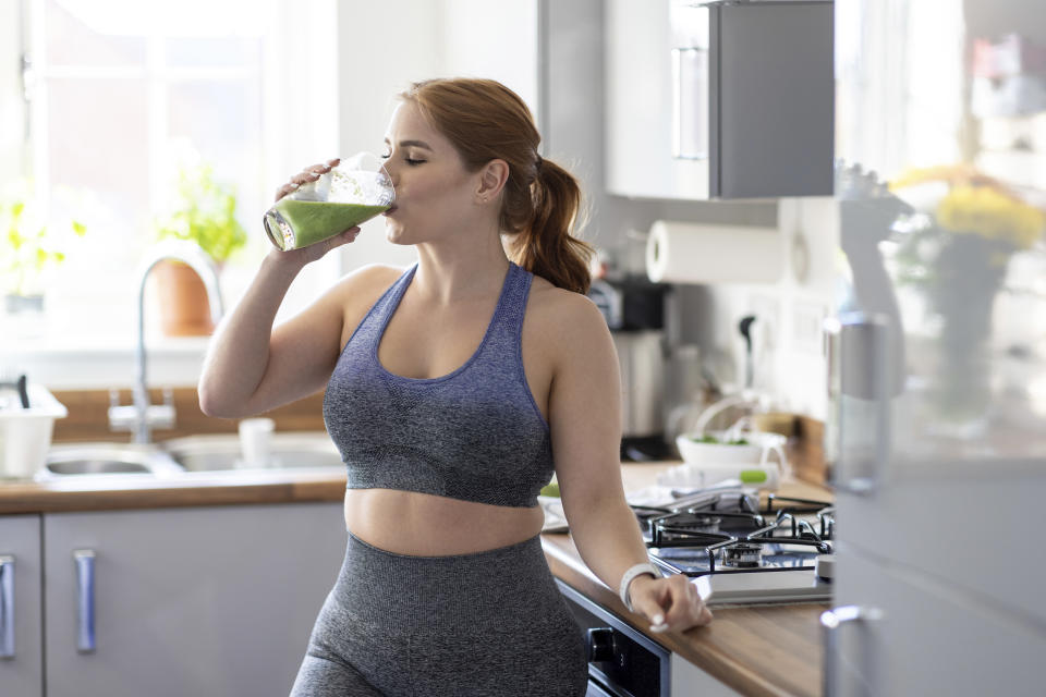 Frau trinkt grünen Smoothie in Sportbekleidung