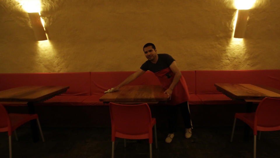 In this Nov. 5, 2017 photo, Gabriel, a blind waiter, prepares a table before the arrival of guests at La Cueva de Rafa, or Rafa’s Cave restaurant, in Quito, Ecuador. Blind waiters guide guests to their tables and deliver tangy fruit juices and appetizing dishes like caramelized vegetables and sweet fried bananas, foods the owner believes can taste even more delightful when diners can’t see what they are eating. (AP Photo/Dolores Ochoa)